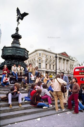 Piccadilly Circus, 1980, impromptu gig by group of music buskers on steps of the Piccadilly Circus Anteros statue roundabout in it's original location. At junction of Regent Street, Piccadilly, Shaftesbury Avenue, London