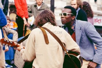 Piccadilly Circus, 1980, impromptu gig by group of music buskers on steps of the Piccadilly Circus Anteros statue roundabout in it's original location. At junction of Regent Street, Piccadilly, Shaftesbury Avenue, London