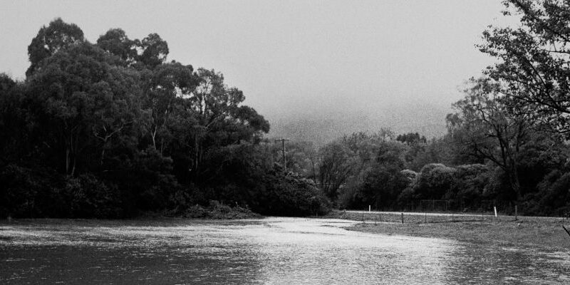 field flooded with water from mittagong creek, trees and mt gibraltar in background engulfed in heavy mist. mount road, bowral, nsw